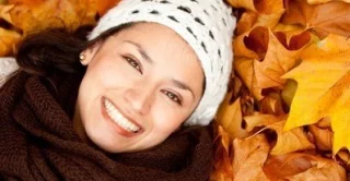 women laying in fall leaves with beautiful and healthy skin
