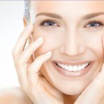 women smiling with hands on her face with beautifully healthy and young skin from laser treatments