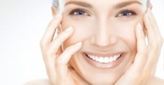 women smiling with hands on her face with beautifully healthy and young skin from laser treatments