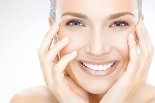 women smiling with hands on her face with beautifully health and young skin after laser treatments