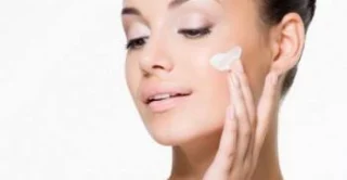 women applying moisturizer to her face