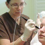Esthetician using thermismooth facial treatment on client's forehead