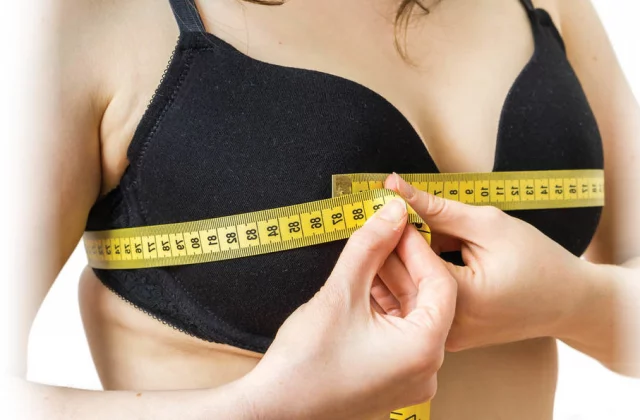 woman with soft tape measure around chest considering Breast Reduction Surgery