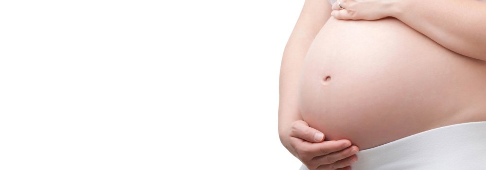close up of pregnant woman's stomach with her hands at top and bottom