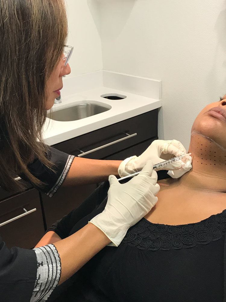 specialist injecting kybella treatments into women's neck to remove double chin fat