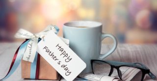 Table top with wrapped gift, coffee cup, and reading glasses on father's day.