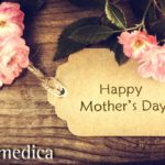 Mother's day card with pink and white flowers resting on wooden table.