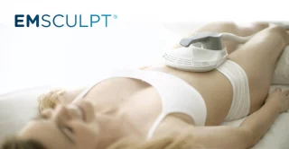 Woman lying down receiving emsculpt treatment.