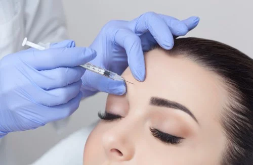 Brunette woman getting dysport injection between the eye brow area.