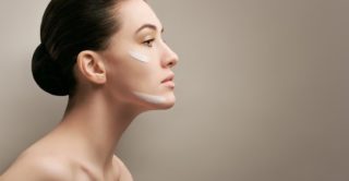 Brunette woman facing right with two cream stripes on her face.