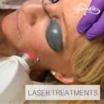 Esthetician using laser facial treatment on client's cheek