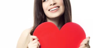 Beautiful young woman in red holding paper heart