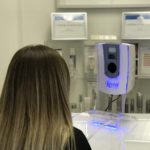 women in a medical room facing a Reveal Imager machine having her picture taken