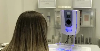 women in a medical room facing a Reveal Imager machine having her picture taken
