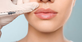 Close up of bottom half of young womens face as she gets lip injections from a doctor