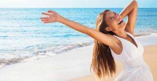 Freedom woman on beach enjoying life with open arms feeling free bliss and success on beach. Happiness Asian girl in white summer dress enjoying ocean