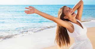 Freedom woman on beach enjoying life with open arms feeling free bliss and success on beach. Happiness Asian girl in white summer dress enjoying ocean
