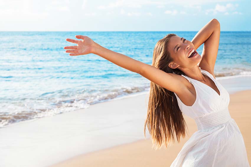 Freedom woman on beach enjoying life with open arms feeling free bliss and success on beach. Happiness Asian girl in white summer dress enjoying ocean