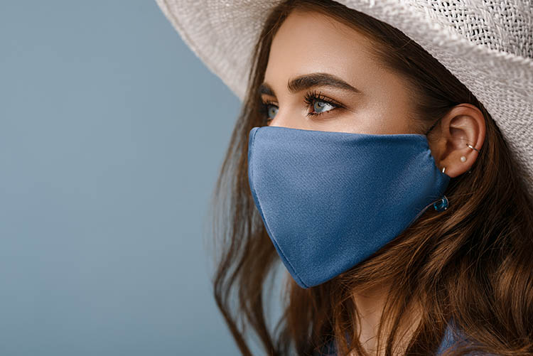 Woman wearing stylish protective face mask showing concern for maskne