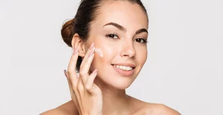 women applying skincare product to face to help enhance the long-term results of a cosmetic treatment