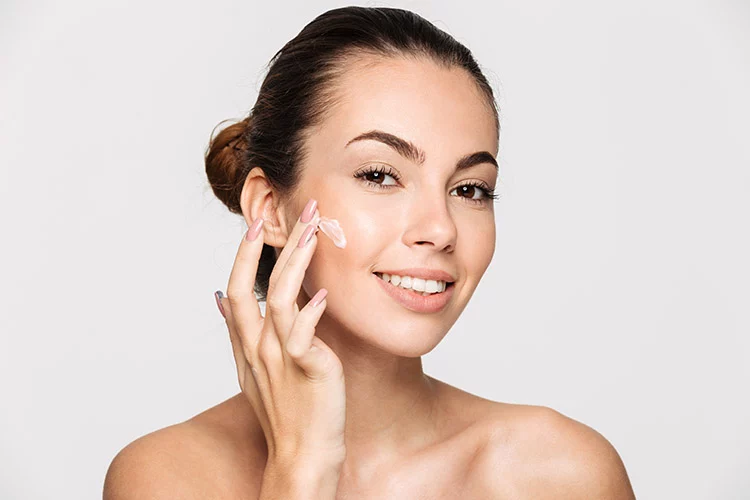 women applying skincare product to face to help enhance the long-term results of a cosmetic treatment