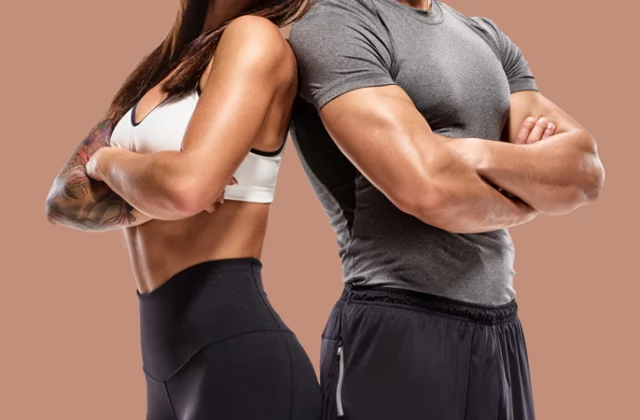 toned couple in workout clothes standing back to back with arms crossed