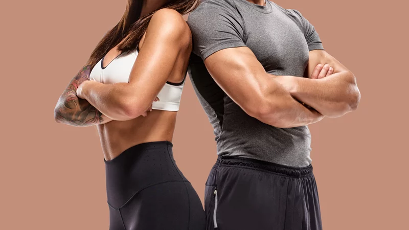 toned couple in workout clothes standing back to back with arms crossed