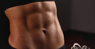 Close up of fit female abs isolated on black background