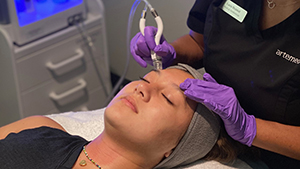 Esthetician using DiamondGlow facial treatment on client's forehead