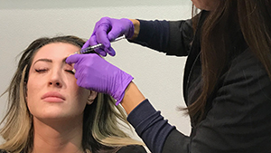 Esthetician using Dysport on client to smooth the appearance of moderate to severe frown lines between the eyebrows