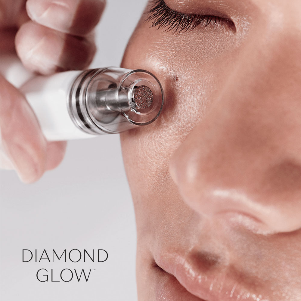 Esthetician using DiamondGlow facial treatment on client's cheek
