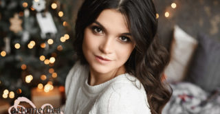 Close up portrait of a young beautiful smiling woman posing in an interior with festive Christmas lights on the background. Brunette model girl with a trendy makeup and perfect smooth skin.