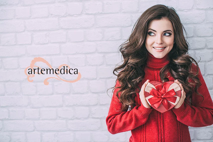 beautiful women in red sweat, smiling and holding a heart shaped valentine's day gift box
