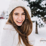 Woman with beautiful, youthful, glowing skin laughing while posing on snow background