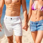 Close up of slim fit masculine couple walking on the beach.
