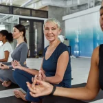 Happy active middle-aged woman in sportswear practice pilates with a group of other women of various ages.
