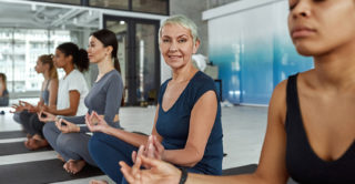 Happy active middle-aged woman in sportswear practice pilates with a group of other women of various ages.