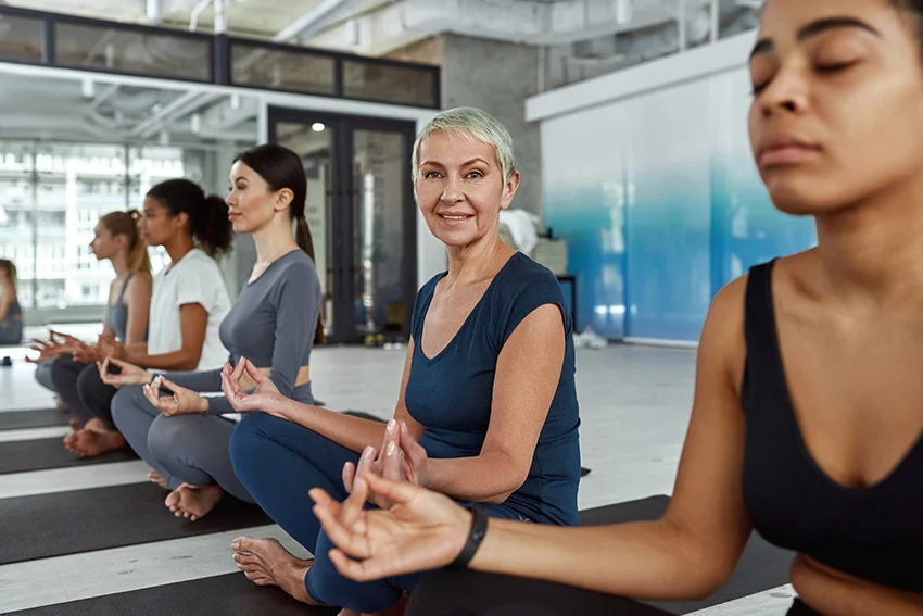 Happy active middle-aged woman in sportswear practice pilates with a group of other women of various ages.