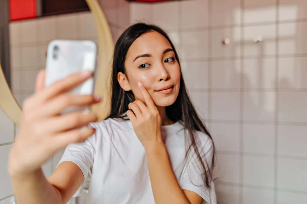woman touching her cheek while taking a selfie in the bathroom