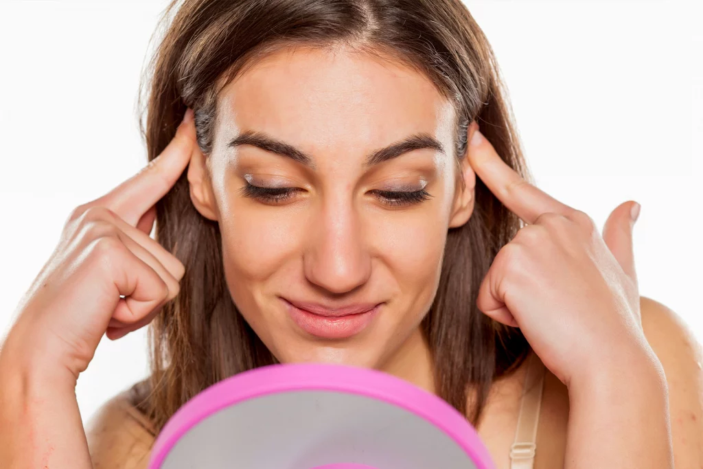 beautiful, young woman insecure about her ears so she pins them back with her fingers