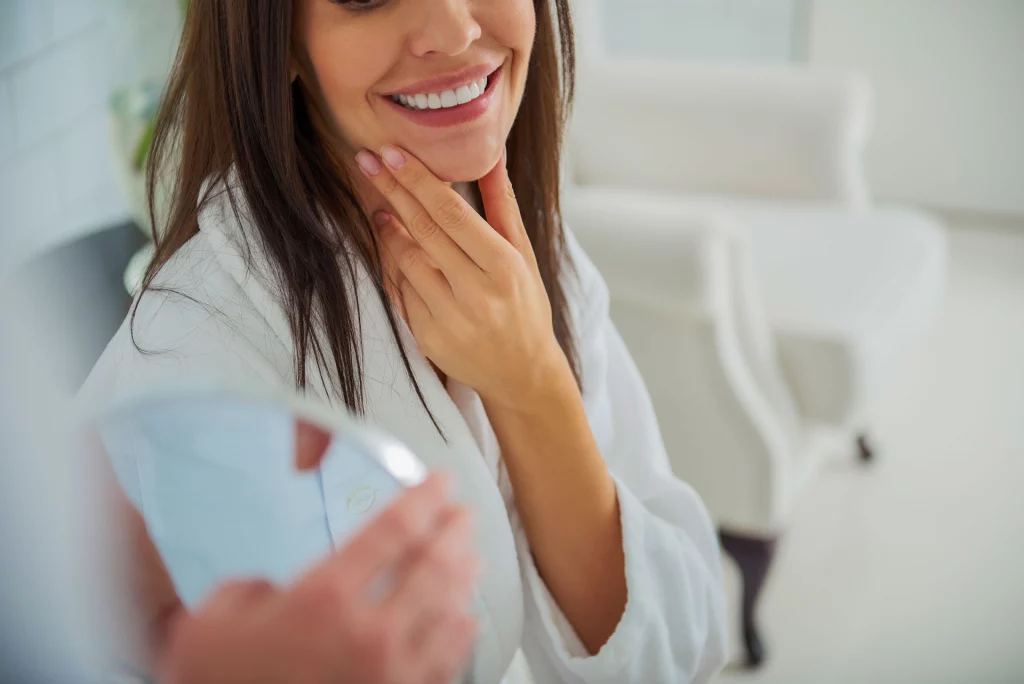 woman admires her appearance in the mirror while stroking her jawline