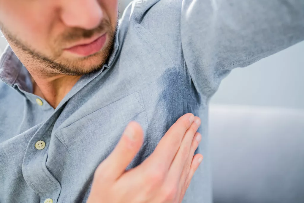 man notices excessive sweating has drenched the underarm of his shirt