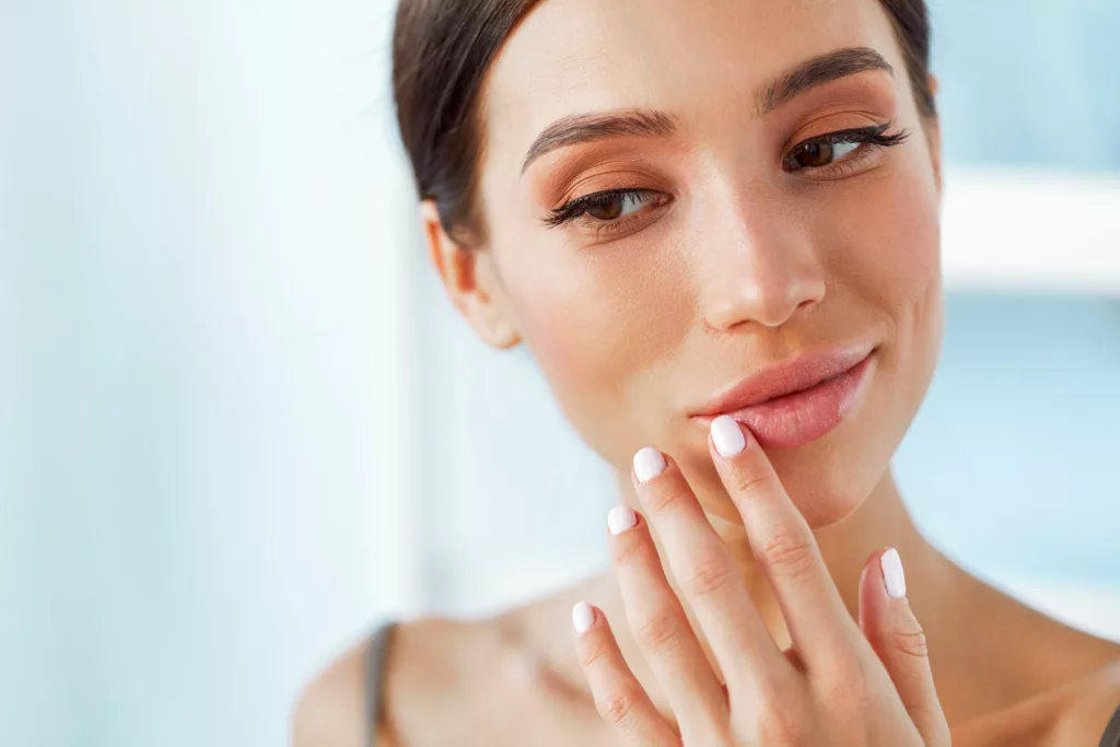 attractive young woman in a camisole admiring her fuller, shapely lips after successful Juvéderm Volbella XC injections
