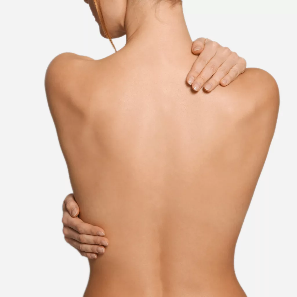 back view of woman with perfect smooth skin embracing herself in a gesture of self-love