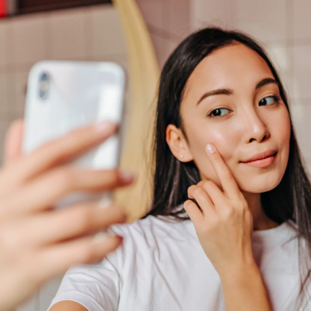 beautiful, young asian woman taking a selfie in the bathroom mirror