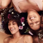 Women of different ages and skins tones laughing together with spring flowers in their hair.