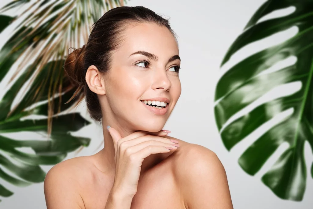 Woman with healthy skin smiling white a blurred tropical themed background