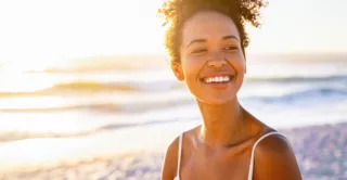 A beautiful young women smiling while walking along the beach during the sunset