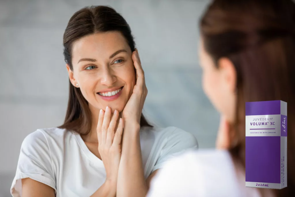 woman admires her appearance in the mirror, including her full, youthful cheeks