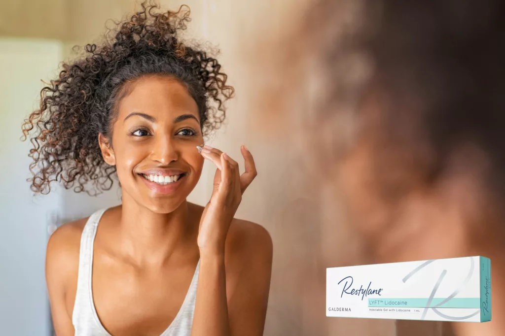 beautiful black woman with full cheeks applies moisturizer while looking at herself in the mirror